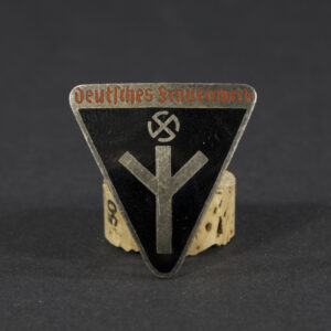 WWII German Deutsches Frauenwerk badge displayed flat, showing its circular shape with detailed emblem and attached pin.
