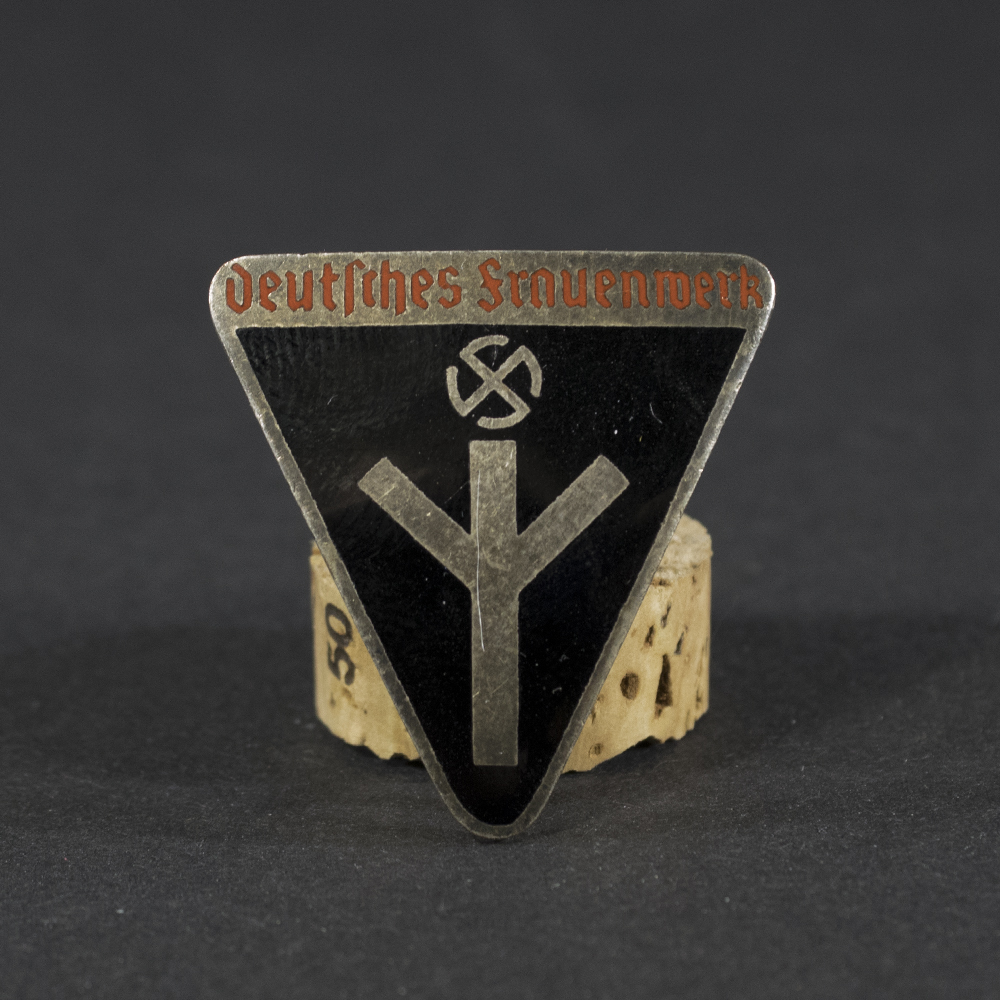 WWII German Deutsches Frauenwerk badge displayed flat, showing its circular shape with detailed emblem and attached pin.