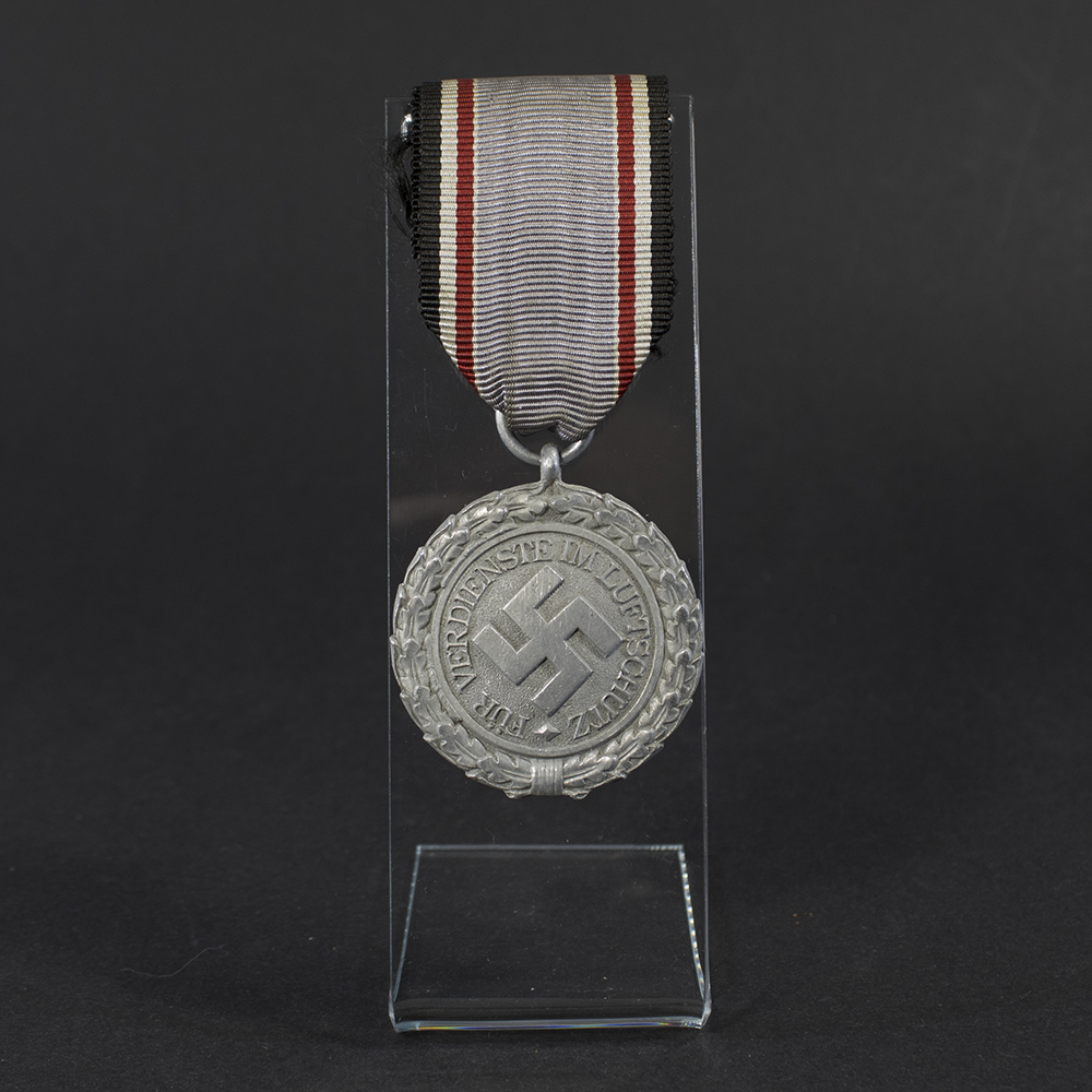 WWII German Luftschutz medal displayed flat, showing its circular shape with detailed embossed design and attached suspension ring.