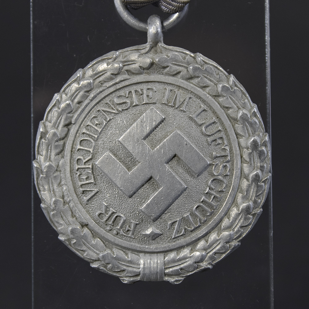 Front side of the WWII German Luftschutz medal, featuring the raised Luftschutz emblem with eagle and swastika surrounded by inscription.