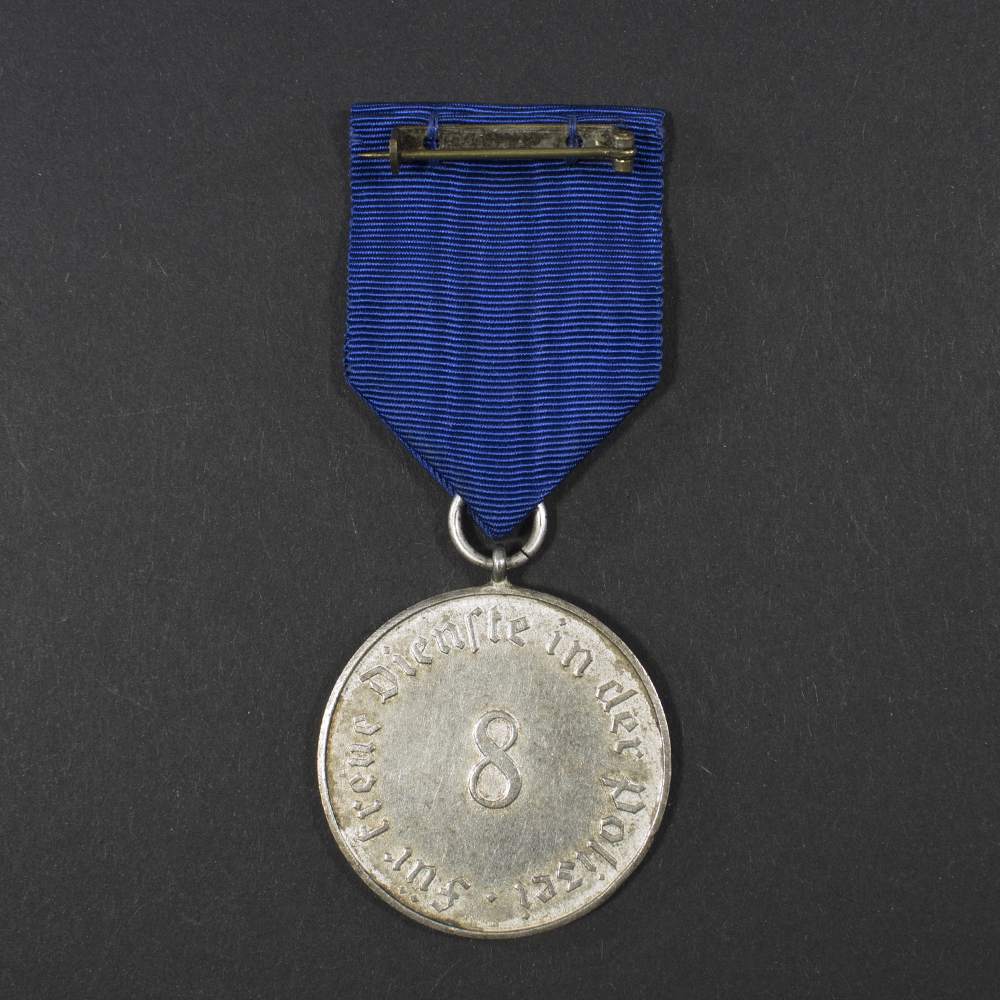 Back side of the WWII German 8-Year Police Long Service Medal displayed flat, showing the smooth surface with raised inscription and slight patina.