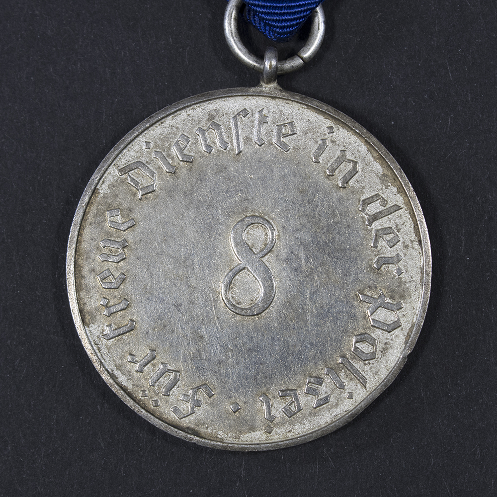 Close-up of the back side of the WWII German 8-Year Police Long Service Medal, focusing on the lettering and texture of the metal.