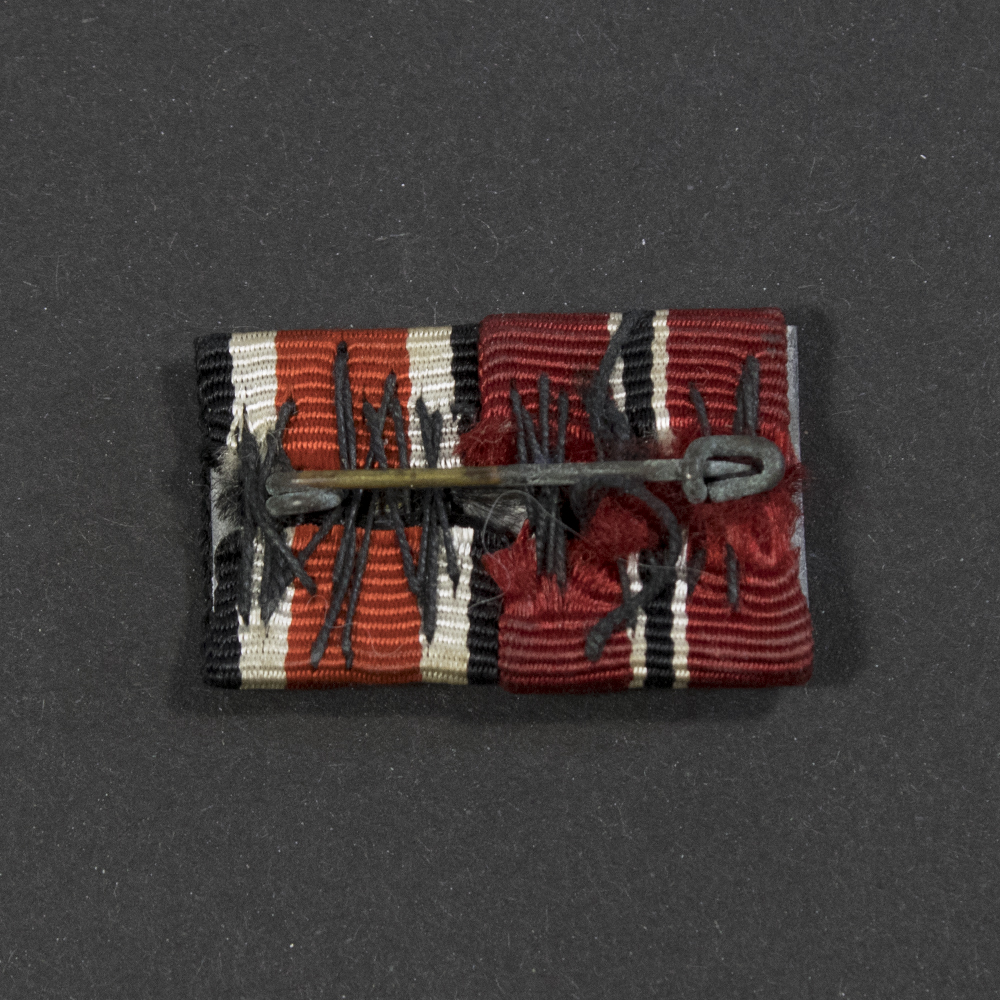 Close-up of the reverse of a WWII ribbon bar, showing stitching and attachment pin.