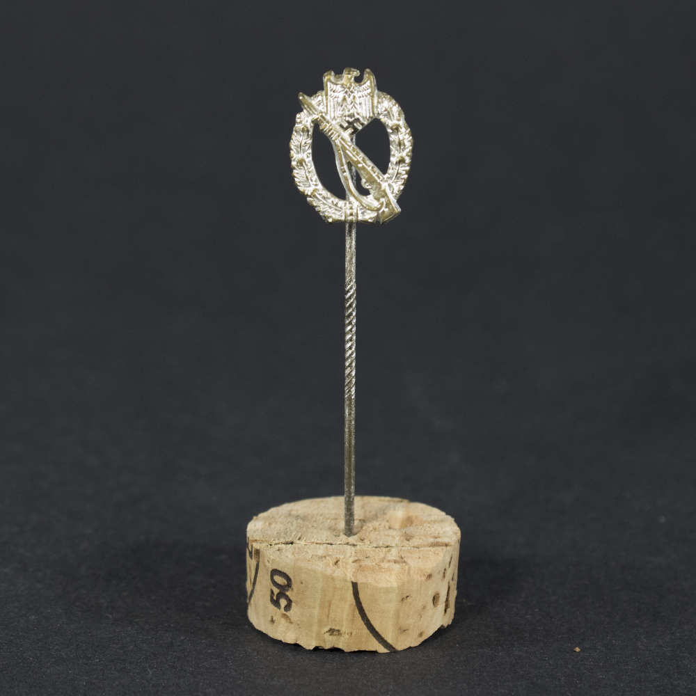 World War II German Silver Infantry Assault Badge stick pin displayed flat, showing the miniature badge with detailed wreath and rifle design attached to a slender pin