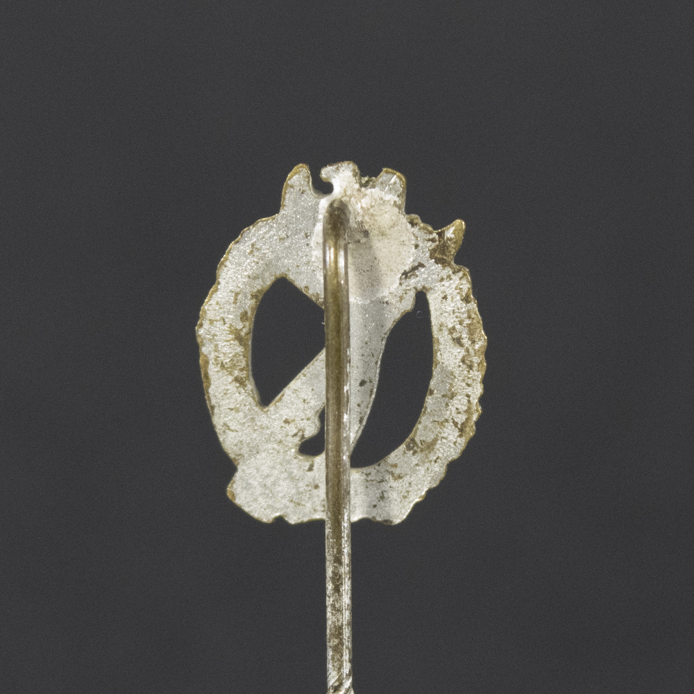 Back side of the WWII German Silver Infantry Assault Badge stick pin, showing the smooth reverse surface and the pin attachment extending downward
