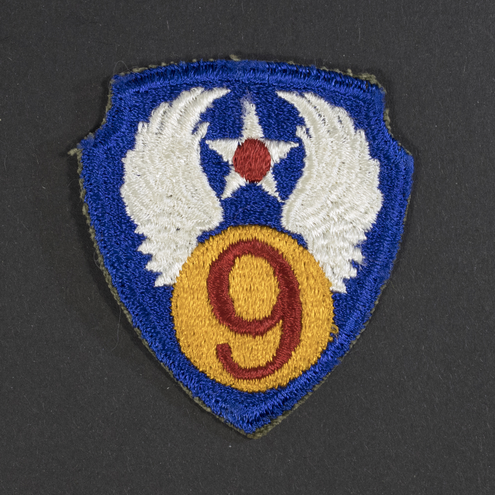 Front of WWII U.S. Army 9th Air Force patch, featuring blue circle with white star and red center, topped by golden wings and number nine.