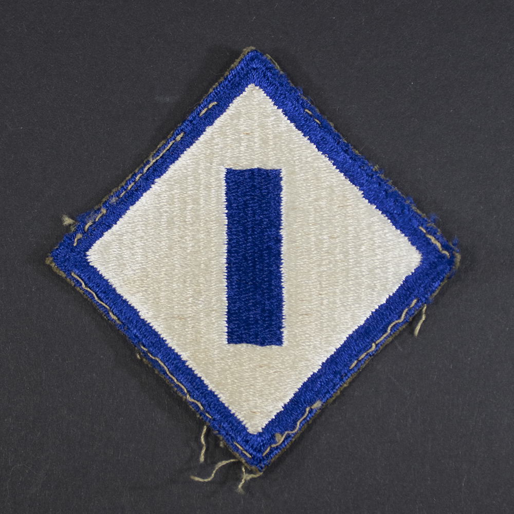 Front of WWII U.S. Army 1st Service Command patch, featuring blue circle with white star and red center, surrounded by a red border.
