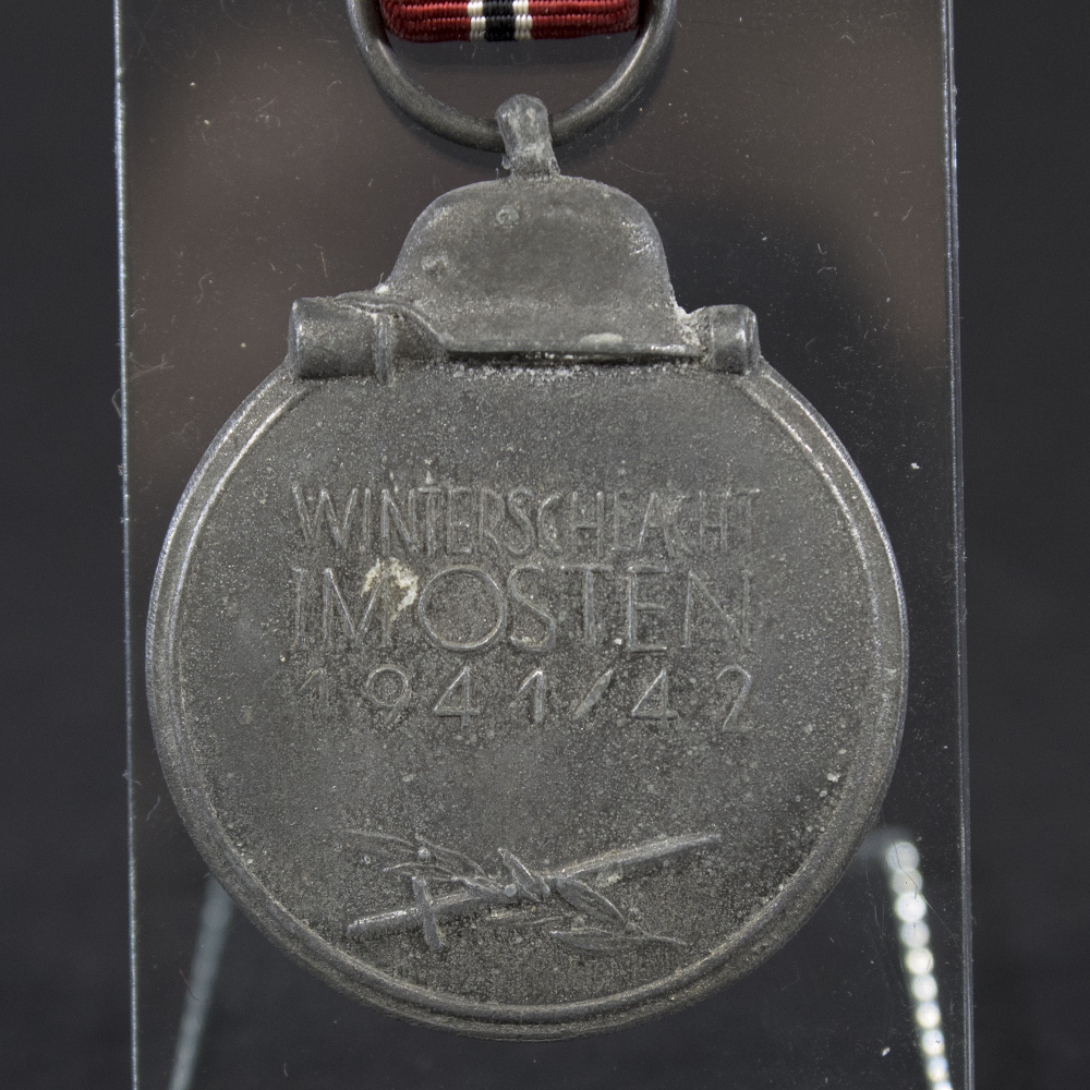 Close-up of the reverse side of a WW2 German Eastern Front Medal, displaying the raised inscription ‘Winterschlacht im Osten 1941/42’ with crossed sword and branch emblem beneath.
