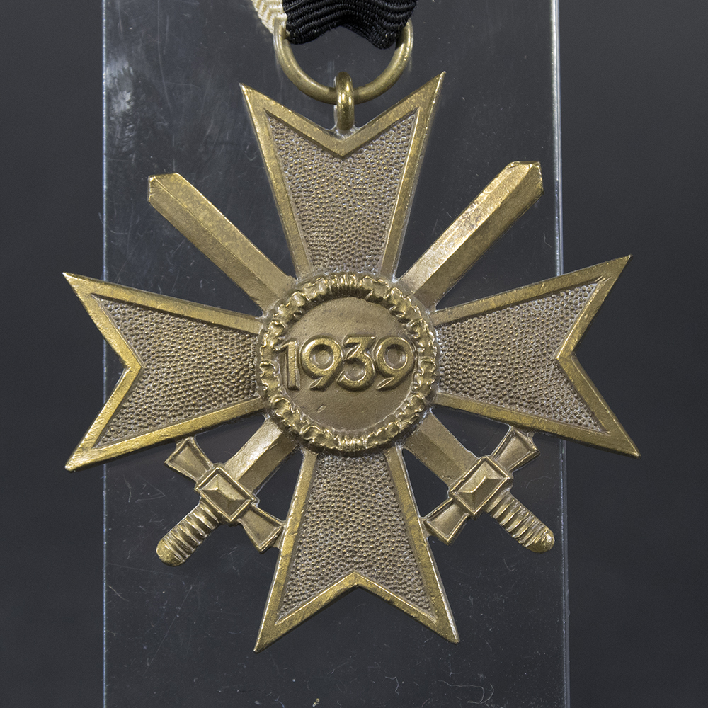 Close-up of the reverse side of the War Merit Cross with Swords, displaying the smooth center bearing the raised '1939' inscription and the detailed bronze finish.