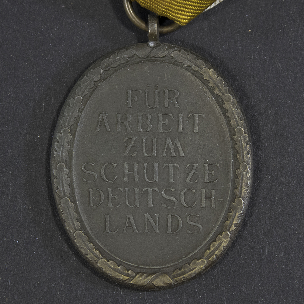 Close-up of the reverse side of the Westwall Medal, showing the inscription ‘Für Arbeit zum Schutze Deutschlands’ surrounded by a wreath.