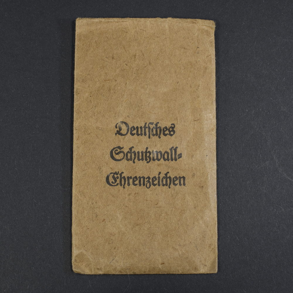 Front view of the brown paper presentation bag for the WW2 Westwall Medal, featuring the printed ‘Deutsches Schutzwall-Ehrenzeichen’ text.