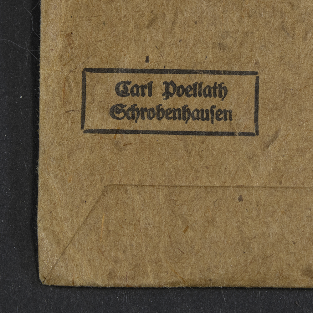 Close-up of the maker stamp ‘Carl Poellath’ on the back of the Westwall Medal bag, showing the manufacturer’s mark faintly impressed into the paper