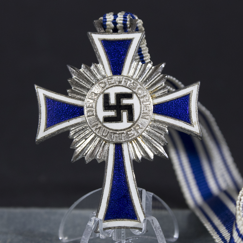 Close-up of the front of a WWII German silver Mother’s Cross, showing the cross shape, enamel surface, and central emblem.