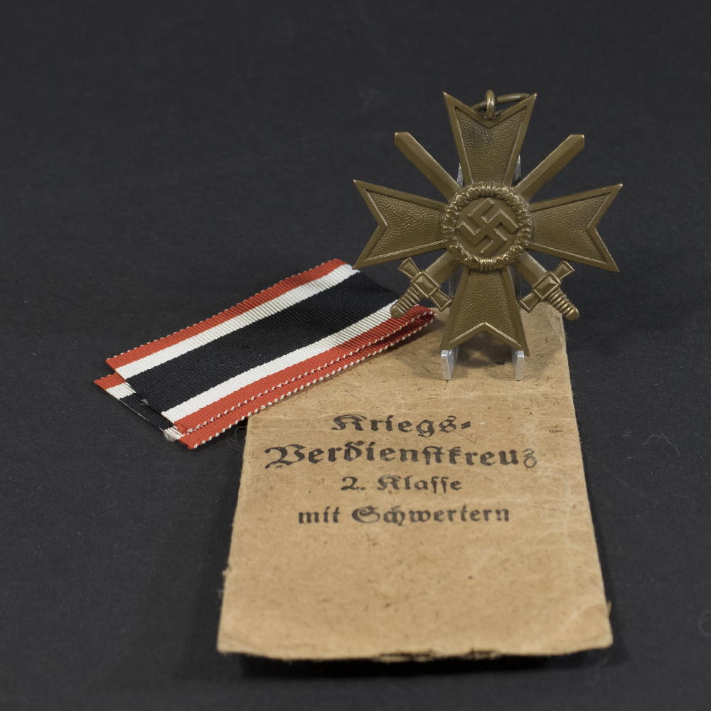 Overview of a WWII German War Merit Cross with Swords, shown together with its original paper bag