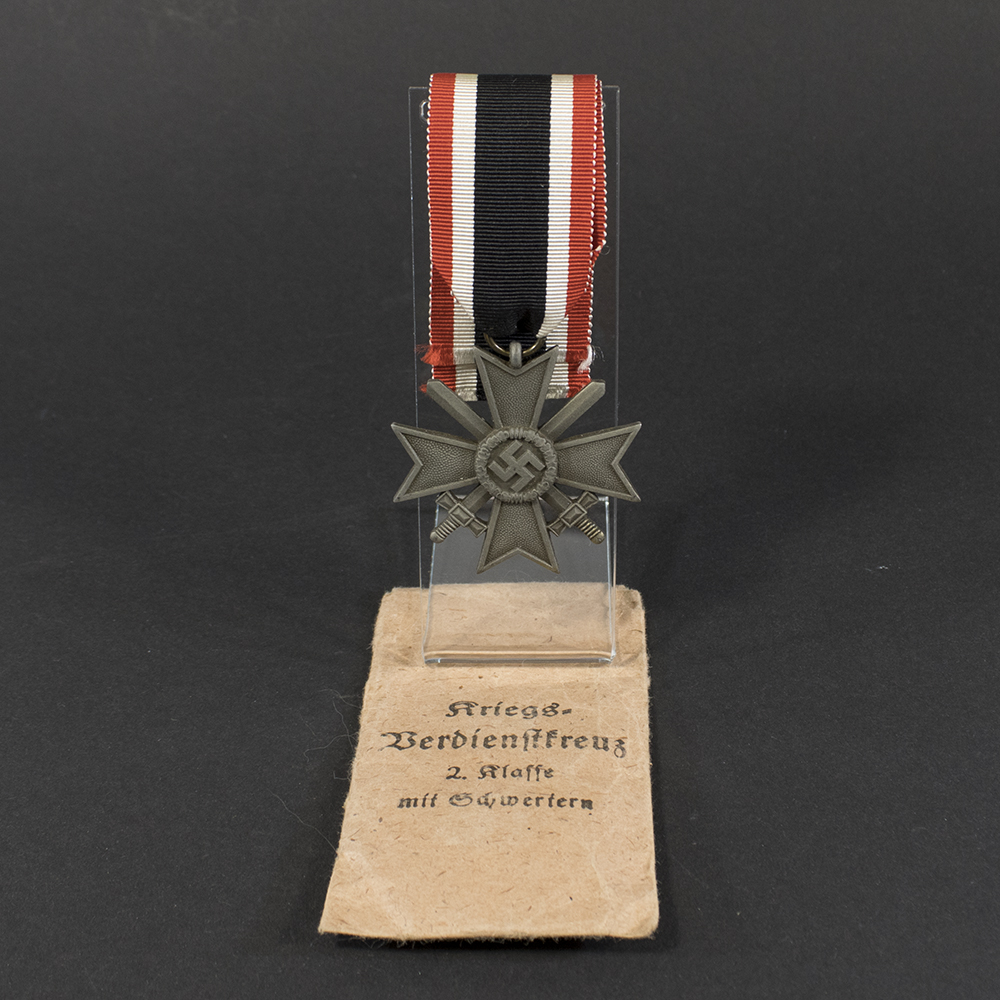Overview of a WWII German War Merit Cross with Swords displayed together with its original paper issue bag.