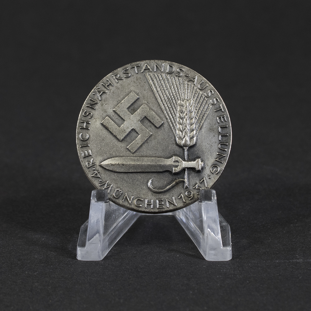 Overview of a WWII German 4th Reichsnährstand Exhibition Munich 1937 tinnie, showing the complete event badge.