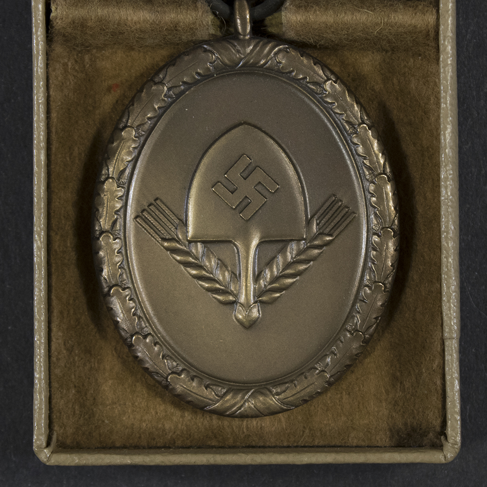 Close‑up of the front of the WWII German RAD 4‑year long service medal, showing the spade emblem and bronze finish.