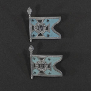 Close‑up of the front side of a small plastic Winterhilfswerk miniature flag associated with the Fahr U.Kraftfahr Einheiten. The rectangular flag shows an eagle emblem and raised lettering molded into the plastic. The surface has a glossy finish, and the relief details and edges are clearly visible despite minor wear.