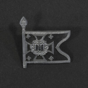 Close‑up of the front side of a small plastic Winterhilfswerk miniature flag associated with the Pioniere Mot. The rectangular flag shows an eagle emblem and raised lettering molded into the plastic. The surface has a glossy finish, and the relief details and edges are clearly visible despite minor wear.