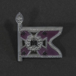 Close‑up of the front side of a small plastic Winterhilfswerk miniature flag associated with the Nebeltruppe . The rectangular flag shows an eagle emblem and raised lettering molded into the plastic. The surface has a glossy finish, and the relief details and edges are clearly visible despite minor wear.