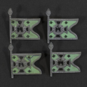 Close‑up of the front side of a small plastic Winterhilfswerk miniature flag associated with the Schützen und Kraftschützen . The rectangular flag shows an eagle emblem and raised lettering molded into the plastic. The surface has a glossy finish, and the relief details and edges are clearly visible despite minor wear.