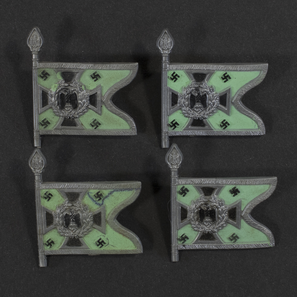 Close‑up of the front side of a small plastic Winterhilfswerk miniature flag associated with the Schützen und Kraftschützen . The rectangular flag shows an eagle emblem and raised lettering molded into the plastic. The surface has a glossy finish, and the relief details and edges are clearly visible despite minor wear.