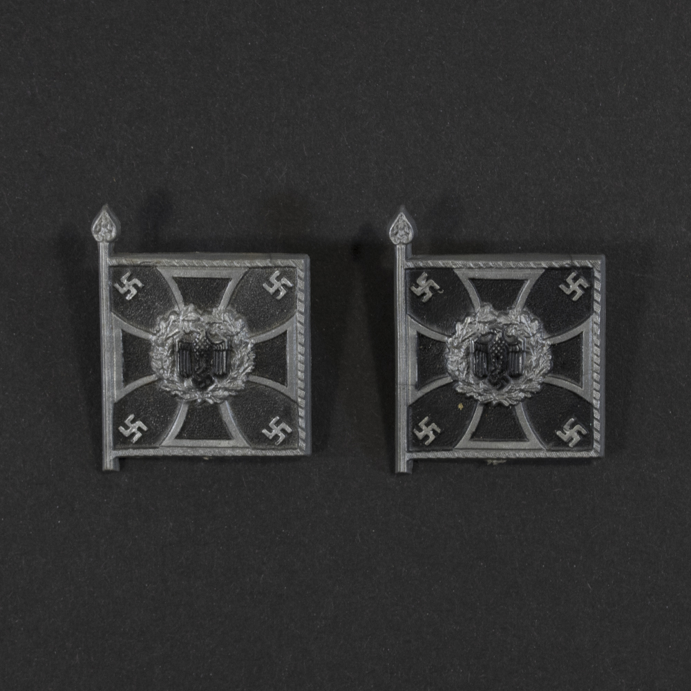 Close‑up of the front side of a small plastic Winterhilfswerk miniature flag associated with the Pioniere. The rectangular flag shows an eagle emblem and raised lettering molded into the plastic. The surface has a glossy finish, and the relief details and edges are clearly visible despite minor wear.