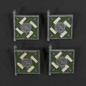 Close‑up of the front side of a small plastic Winterhilfswerk miniature flag associated with the Regiment General Göring. The rectangular flag shows an eagle emblem and raised lettering molded into the plastic. The surface has a glossy finish, and the relief details and edges are clearly visible despite minor wear.