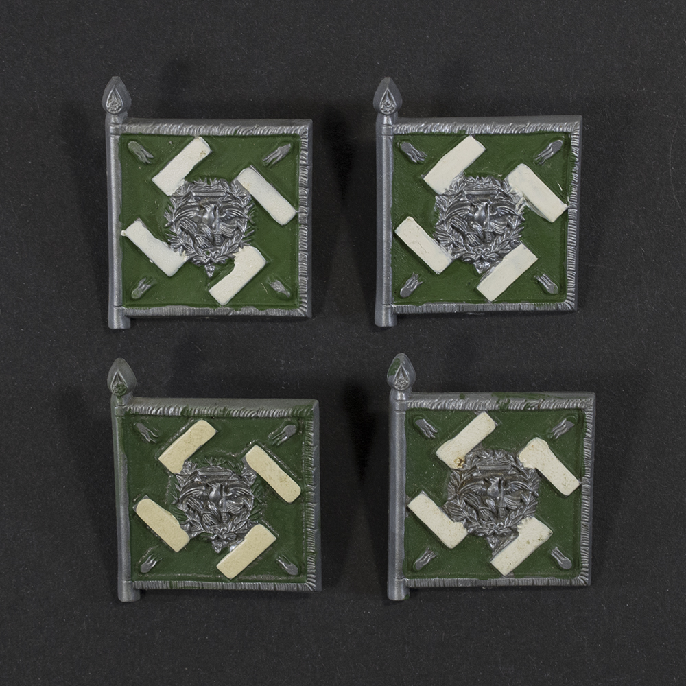 Close‑up of the front side of a small plastic Winterhilfswerk miniature flag associated with the Regiment General Göring. The rectangular flag shows an eagle emblem and raised lettering molded into the plastic. The surface has a glossy finish, and the relief details and edges are clearly visible despite minor wear.