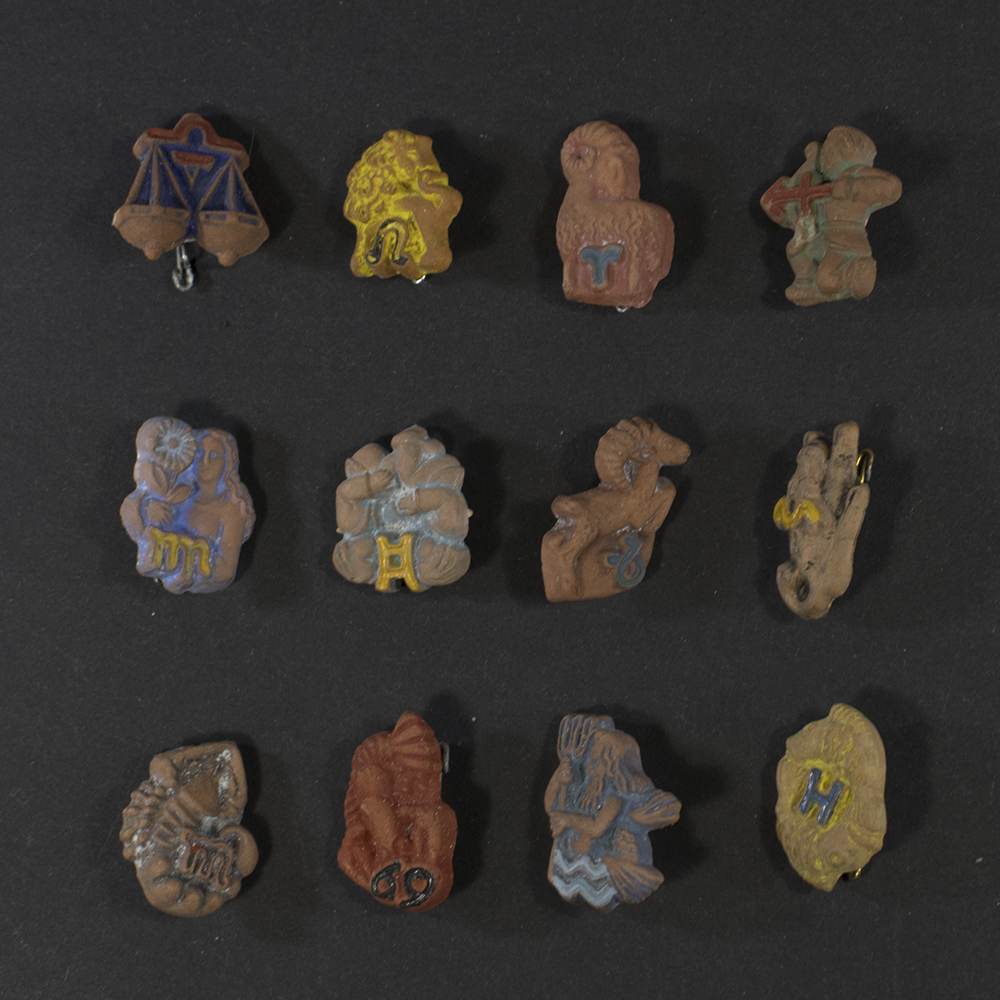 Front view of a complete set of twelve German WWII Winterhilfswerk Tierkreiszeichen ceramic badges, each representing a different zodiac sign, arranged together as a full series.