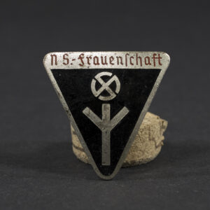 A German World War II-era Deutsches Frauenwerk badge displayed against a plain background, showing its overall shape and design with a central emblem and surrounding details.