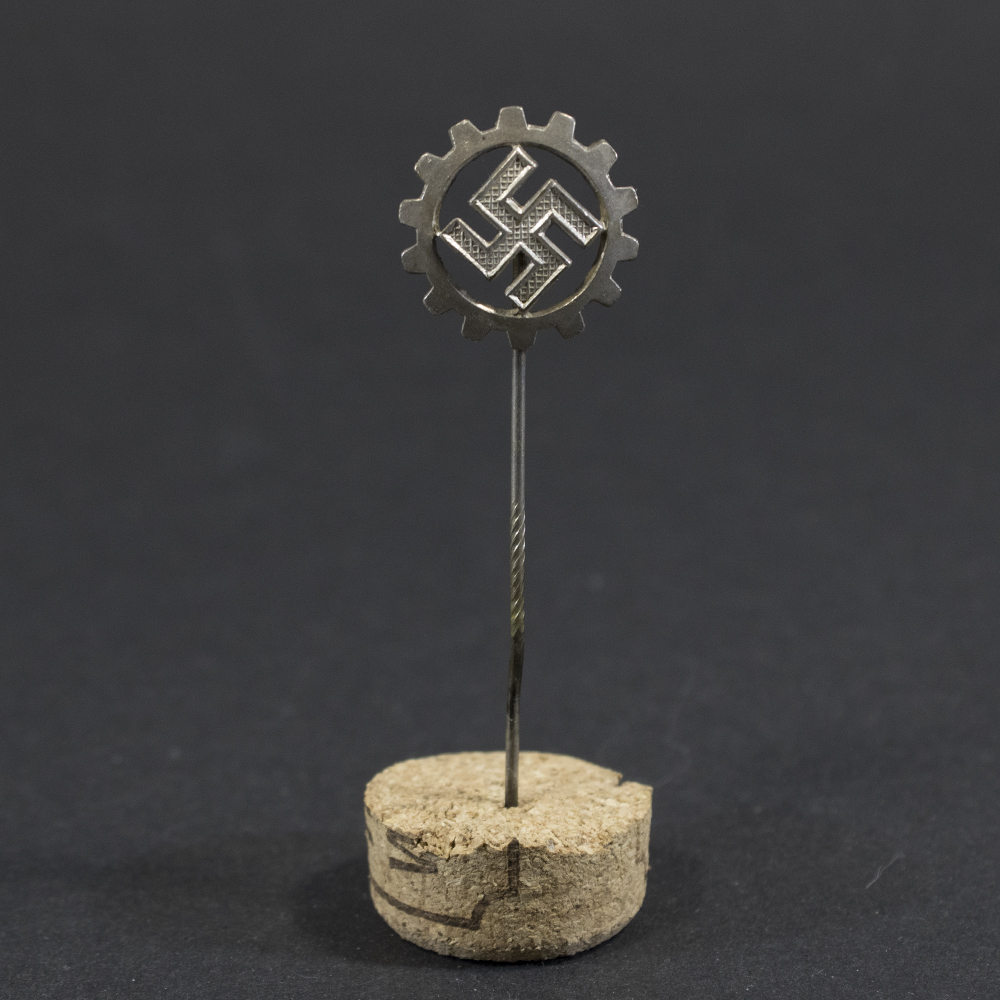 Overview of a World War II-era German DAF (Deutsche Arbeitsfront) membership pin displayed on a neutral background, showing its circular form and enamel design.