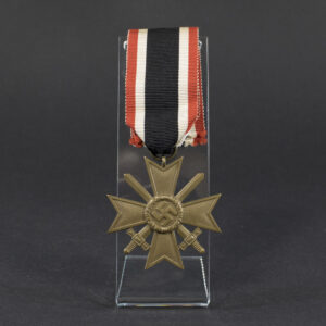 Overview of a World War II-era German War Merit Cross with swords, shown with its original ribbon, displaying the bronze cross suspended from a striped ribbon against a neutral background.