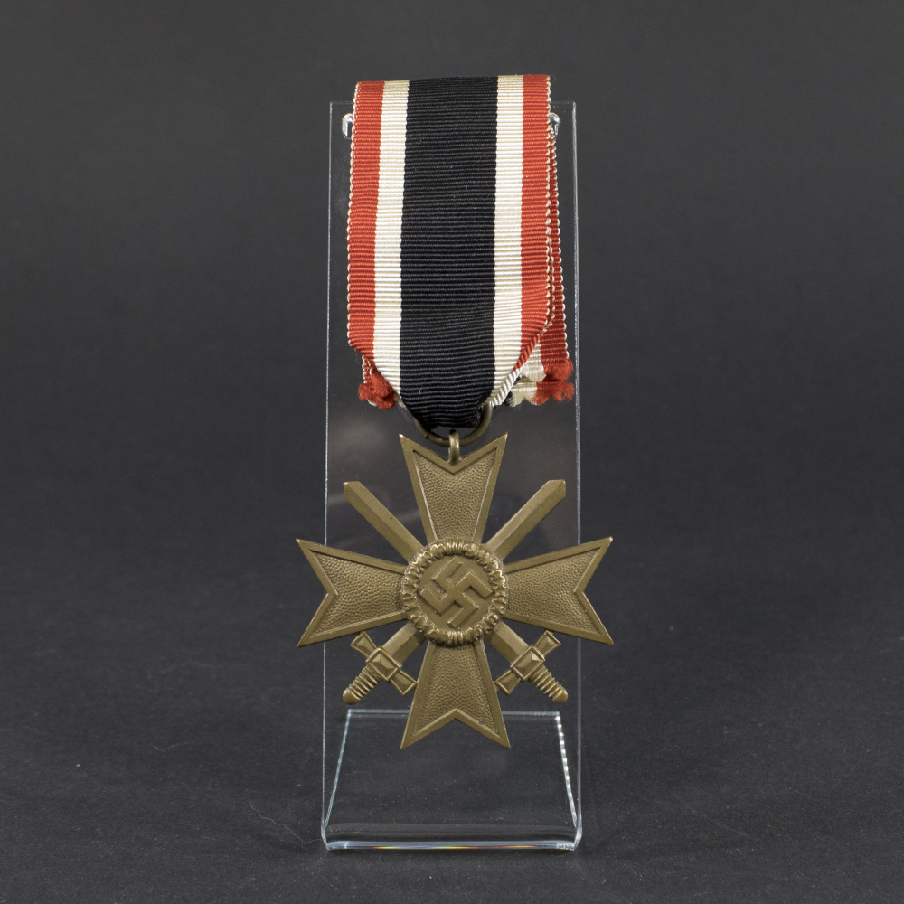 Overview of a World War II-era German War Merit Cross with swords, shown with its original ribbon, displaying the bronze cross suspended from a striped ribbon against a neutral background.