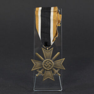 Overview of a World War II-era German War Merit Cross with swords, shown with its original ribbon, displaying the bronze cross suspended from a striped ribbon against a neutral background.