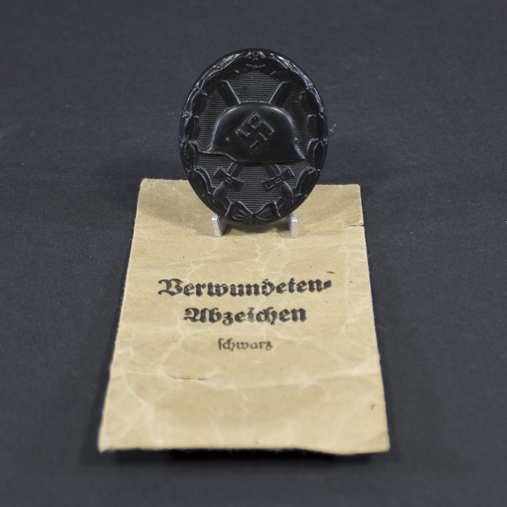 WW2 Black Wound Badge with maker marked bag overview showing badge and original packaging