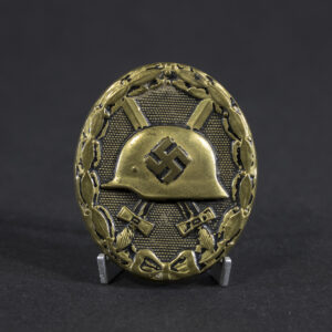 Full view of a WWII German Black Wound Badge. The oval-shaped badge features a military helmet over crossed swords within a laurel wreath. Most of the original black finish has worn away, exposing the underlying metal and creating a heavily aged appearance with visible wear and patina.