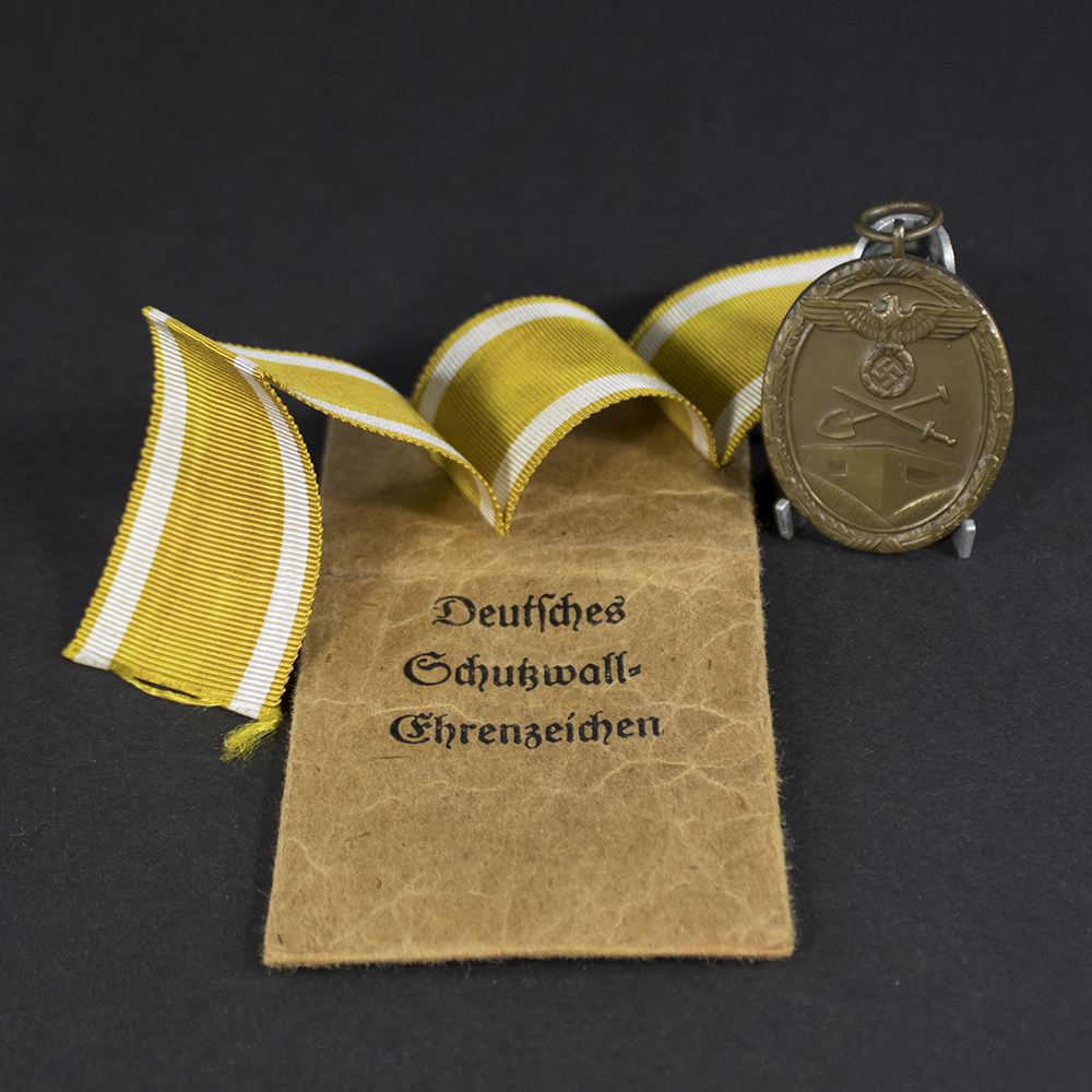 Overview of a German West Wall Medal (Deutsches Schutzwall-Ehrenzeichen) with its original issue bag, awarded for service on the Siegfried Line.