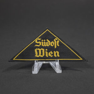 Overview of a Hitler Youth (HJ) “Gebietsdreieck Südost Wien” cloth insignia, triangular in shape with embroidered lettering, shown in full view to display its overall condition, color, and construction.