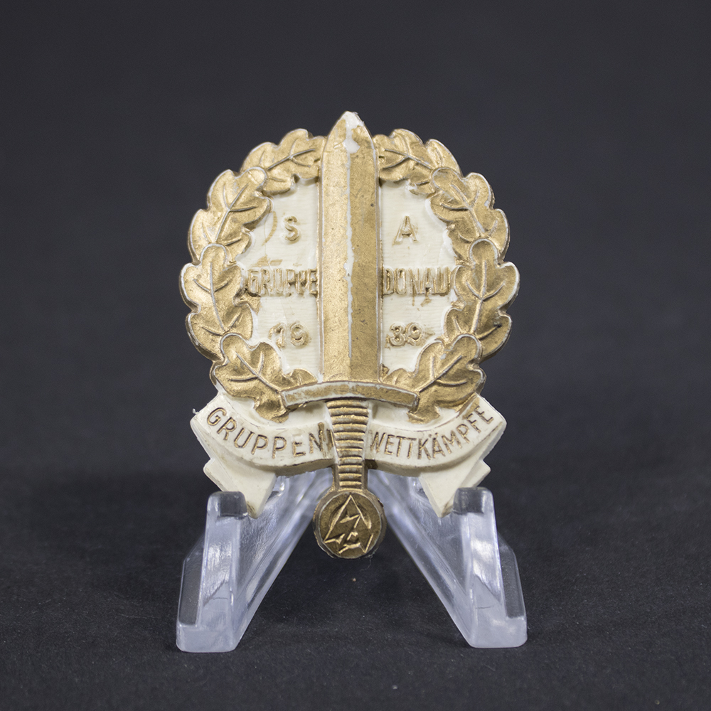 Overview of a World War II-era German tinnie commemorating SA Gruppenwettkämpfe Donau, shown in full view to display the complete design, shape, and overall condition of the badge.
