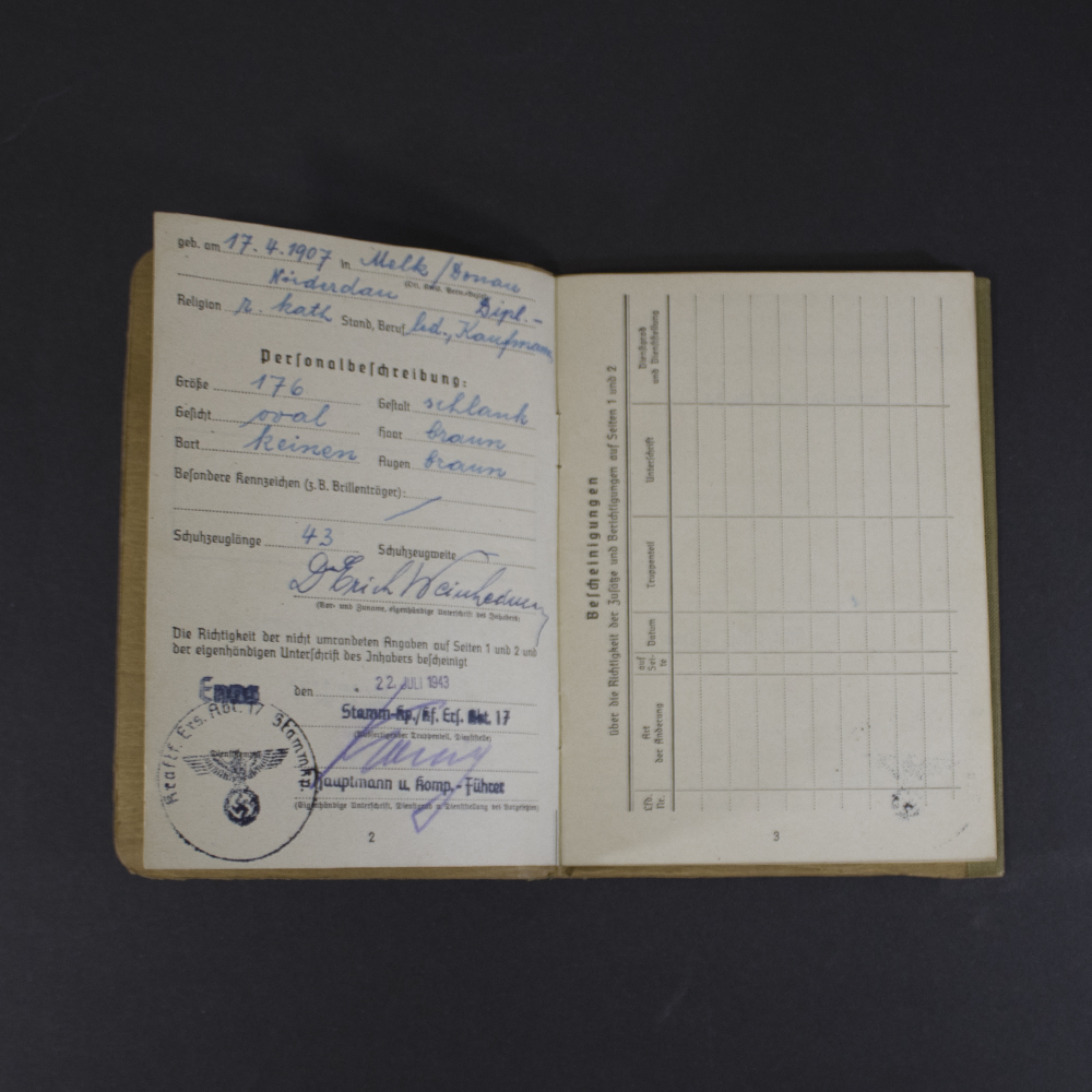 Interior pages of a German WWII Soldbuch displaying the soldier's personal information, physical description, official unit stamp, signature, and verification entries.
