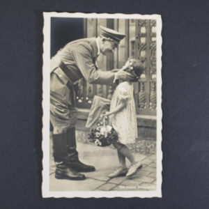Black-and-white Photo-Hoffmann postcard titled “Die Kleine Gratulantin,” showing Adolf Hitler bending down to greet a young girl holding a bouquet of flowers and a wrapped gift. The child stands in front of an ornate building entrance, and the photograph is presented with a decorative scalloped border.