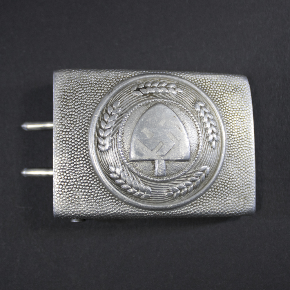Front view of a silver-toned German RAD belt buckle from World War II featuring a shovel and swastika encircled by ears of grain.