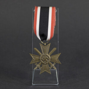 Front view of a WW2 German War Merit Cross 2nd Class with Swords, featuring a pebbled bronze Maltese cross, crossed swords, and central swastika attached to its original red, white, and black ribbon on a clear display stand.