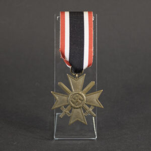 Front view of a WW2 German War Merit Cross 2nd Class with Swords, featuring a pebbled bronze Maltese cross, crossed swords, and central swastika attached to its original red, white, and black ribbon on a clear display stand.