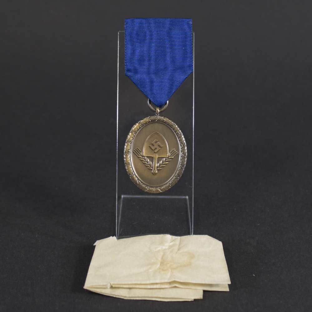 WW2 German RAD 4 Year Service Medal displayed on stand with original blue ribbon and tissue paper packet.